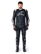 Piloto masculino con la chaqueta de cuero Alpinestars Missile V3 Ignition en color negro, combinada con pantalones de cuero, guantes y botas a juego, con logotipos blancos de Alpinestars y detalles en rojo, diseñada para un rendimiento de competición profesional.