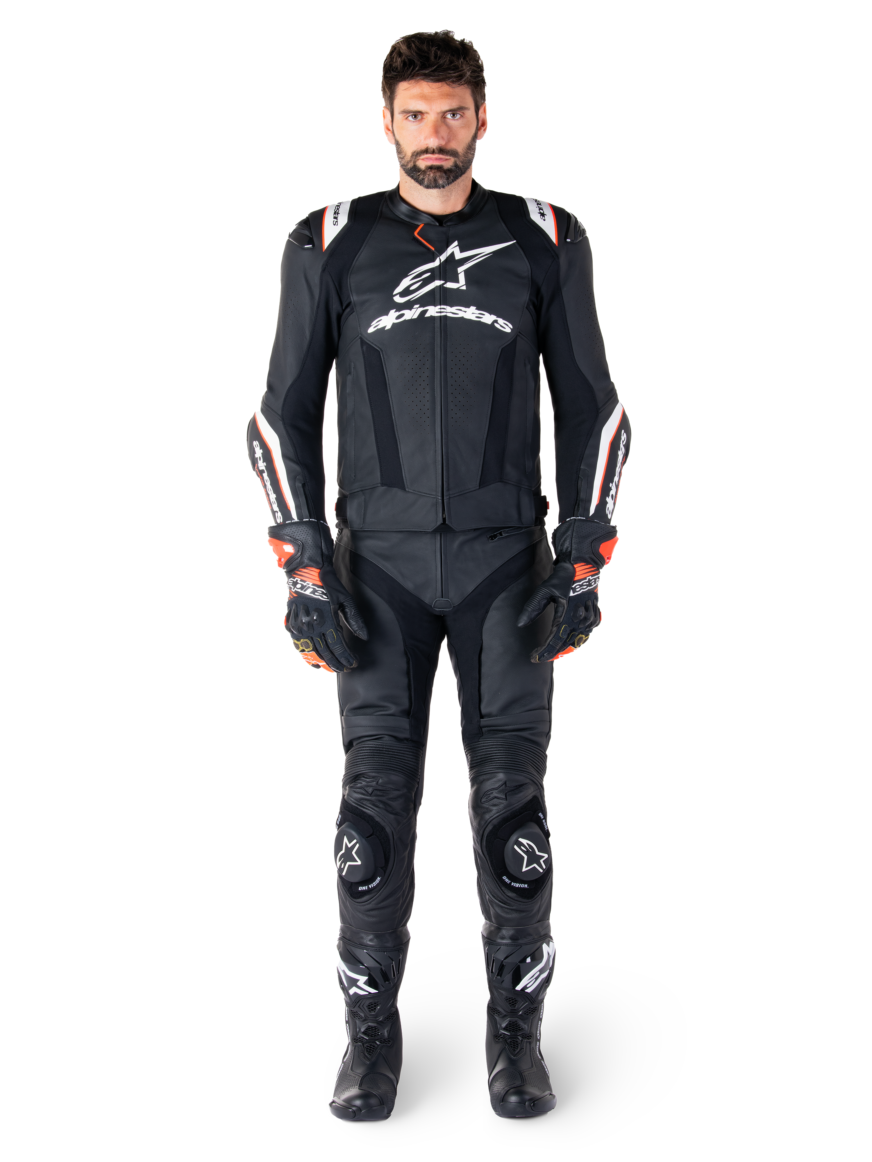 Piloto masculino con la chaqueta de cuero Alpinestars Missile V3 Ignition en color negro, combinada con pantalones de cuero, guantes y botas a juego, con logotipos blancos de Alpinestars y detalles en rojo, diseñada para un rendimiento de competición profesional.