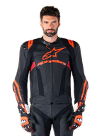 Chaqueta de cuero Alpinestars Missile V3 Ignition, chaqueta de carreras para moto, negra y roja fluo, usada con guantes de carreras y pantalones de cuero a juego, con ventilación perforada y marca Alpinestars destacada, equipamiento profesional para carreras