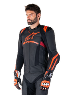 Chaqueta de cuero Alpinestars Missile V3 Ignition, negra con detalles en rojo flúor y rojo oscuro, vestida por un modelo masculino con guantes de carreras y pantalones de cuero a juego, con logotipos llamativos de Alpinestars, paneles de cuero perforado y protectores externos en los hombros, equipo profesional de carreras de motos