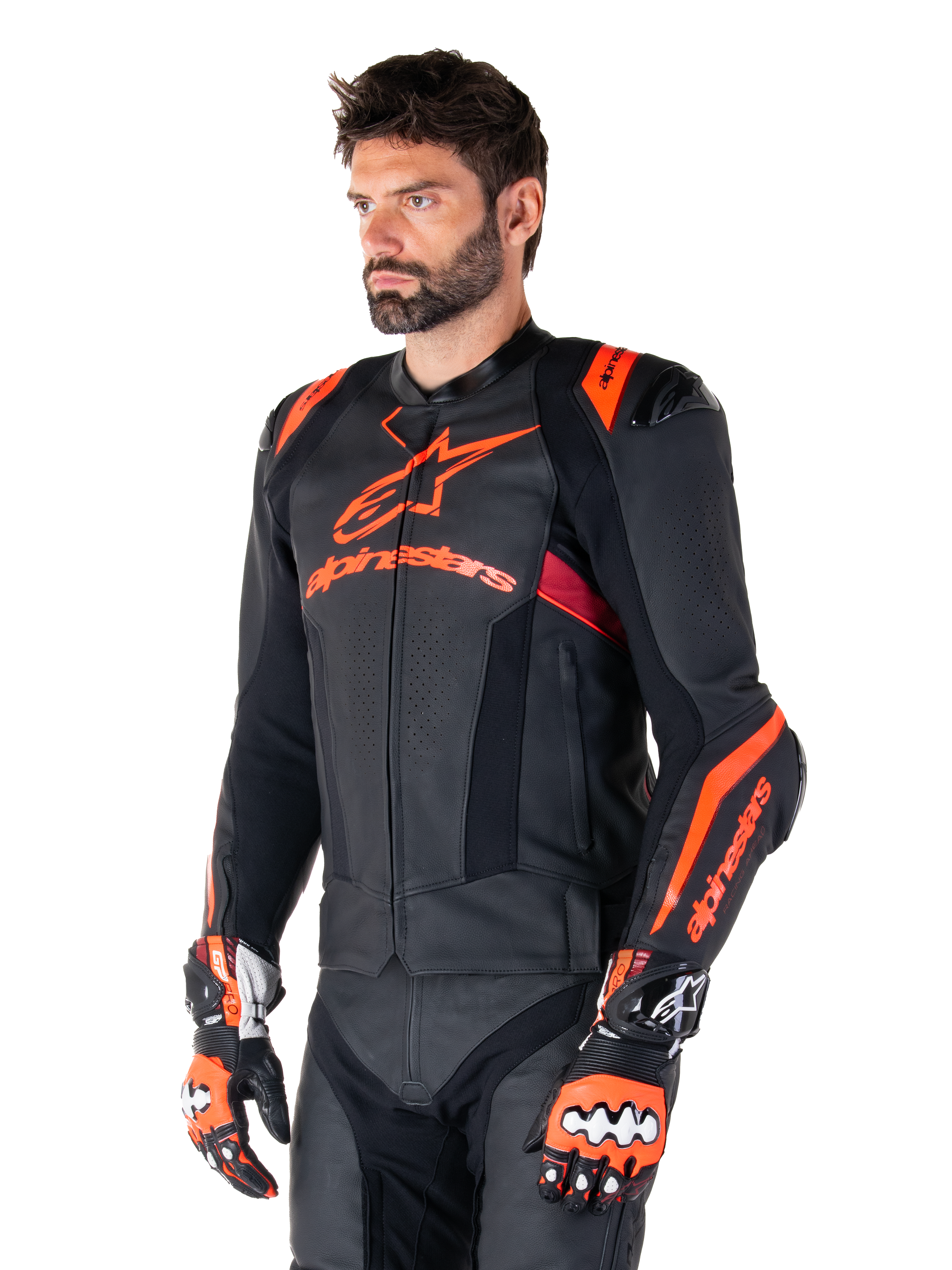 Chaqueta de cuero Alpinestars Missile V3 Ignition, negra con detalles en rojo flúor y rojo oscuro, vestida por un modelo masculino con guantes de carreras y pantalones de cuero a juego, con logotipos llamativos de Alpinestars, paneles de cuero perforado y protectores externos en los hombros, equipo profesional de carreras de motos