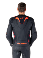 Chaqueta de cuero Alpinestars Missile V3 Ignition, vista trasera, negro con detalles en rojo flúor y rojo oscuro, con joroba aerodinámica deportiva, marca Alpinestars en la espalda, combinada con pantalones de montar de cuero negros a juego, equipamiento de alto rendimiento para carreras de motos