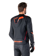 Alpinestars Missile V3 Ignition Leather Jacket, chaqueta deportiva de competición para hombre, negra con detalles en Rojo Fluo, vista trasera con la delgada joroba aerodinámica y el logotipo de Alpinestars en la parte inferior de la espalda, combinada con pantalones de cuero negros y guantes de carreras, diseño profesional de motociclismo deportivo