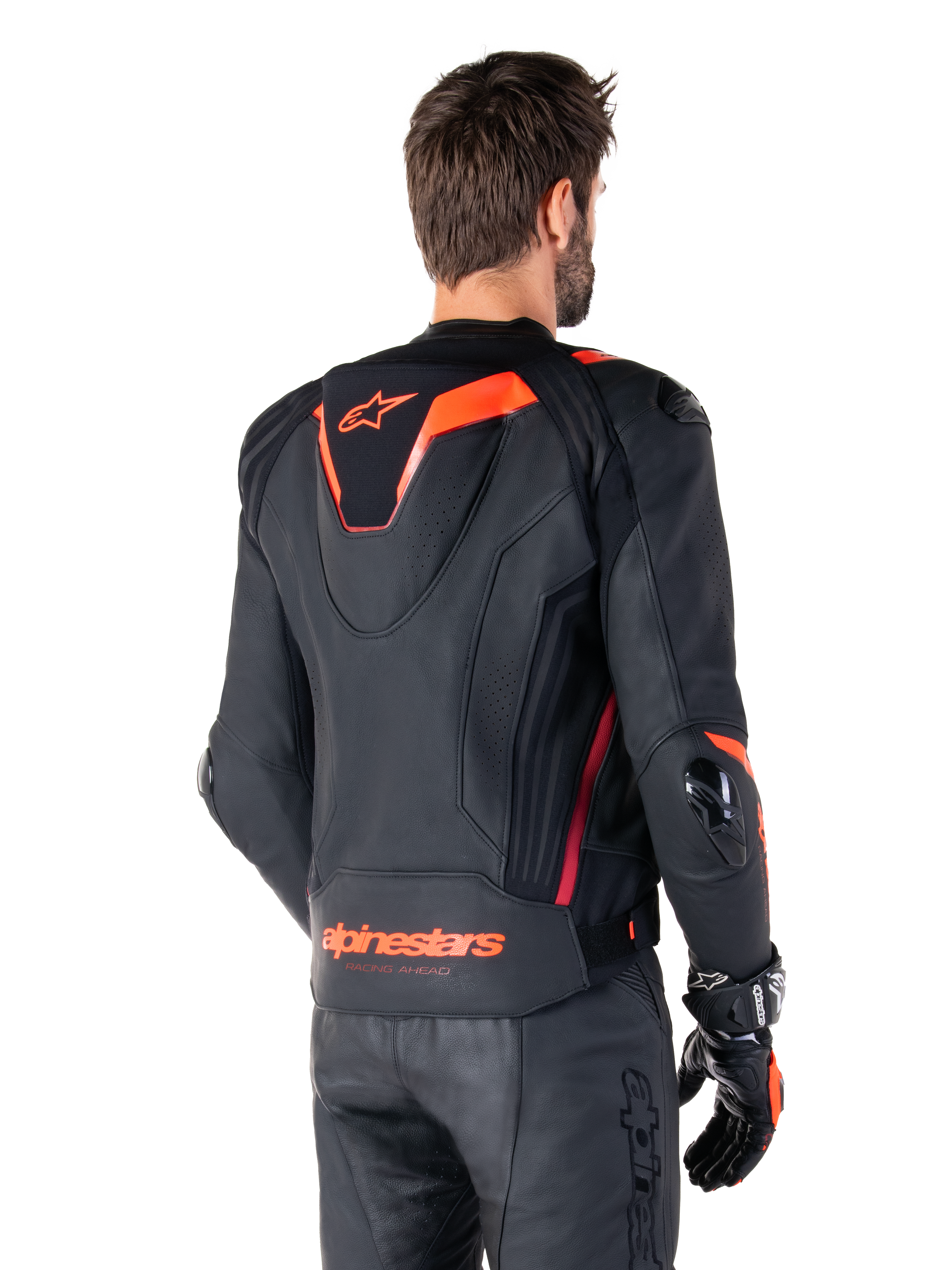 Alpinestars Missile V3 Ignition Leather Jacket, chaqueta deportiva de competición para hombre, negra con detalles en Rojo Fluo, vista trasera con la delgada joroba aerodinámica y el logotipo de Alpinestars en la parte inferior de la espalda, combinada con pantalones de cuero negros y guantes de carreras, diseño profesional de motociclismo deportivo