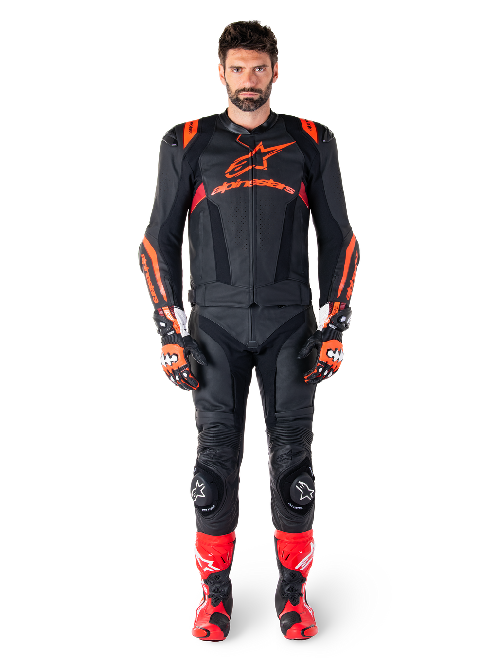 Modelo masculino con la chaqueta de cuero Alpinestars Missile V3 Ignition en color negro, rojo flúor y rojo oscuro, equipamiento completo de competición para moto con pantalones de cuero a juego, guantes y botas de carreras, marca Alpinestars destacada en el pecho, pose frontal, atuendo profesional de conducción deportiva