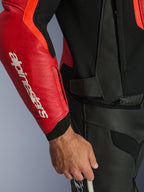 Chaqueta de cuero Alpinestars GP Force V2 Air, rojo y rojo flúor, primer plano de la manga de cuero perforado con el logotipo de Alpinestars en blanco, paneles negros texturizados y cremallera de conexión en la cintura, protección premium para conducción deportiva