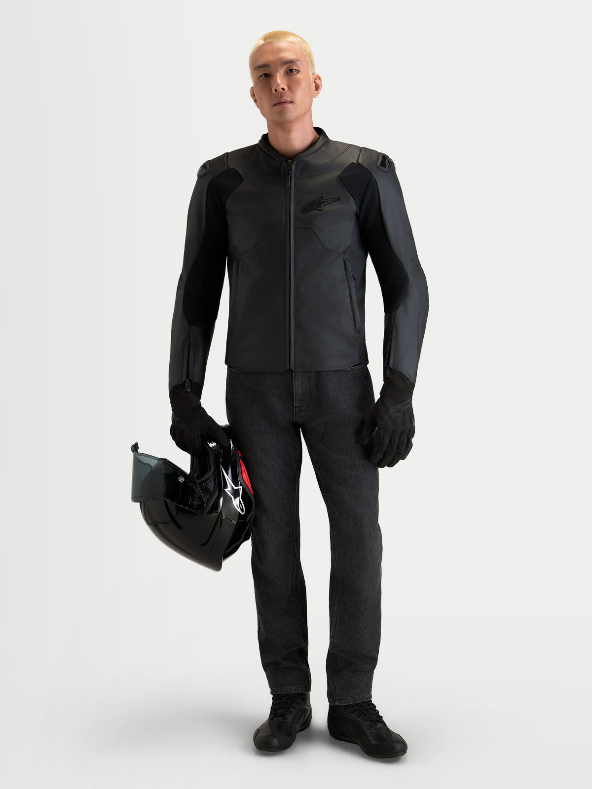 Alpinestars Caliber V2, chaqueta de cuero para moto para hombre, color negro, con protección con certificación AA, hombros DFS de perfil bajo y construcción de piel vacuna flor entera, vestida por un modelo masculino que sostiene un casco negro