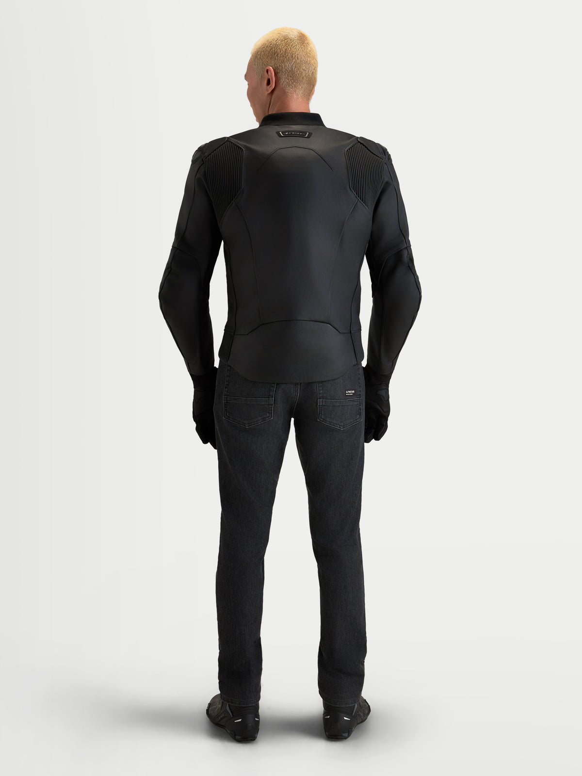 Alpinestars Caliber V 2, chaqueta de moto de cuero negra, vista trasera en modelo con equipo de carretera