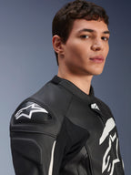 Chaqueta de cuero Alpinestars GP Plus V4, negra y blanca, usada por un modelo masculino, con logotipo de Alpinestars en blanco y deslizadores de hombro DFS, construcción de cuero derivada de la competición para conducción deportiva