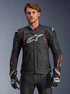 Alpinestars Dusk Airflow Leather Jacket, chaqueta de cuero para carreras de motos, negra con detalles en rojo flúor y blanco, con perforaciones extensas para ventilación, logotipo blanco en el pecho y deslizadores de hombros externos, vestida por un modelo con guantes de carreras a juego