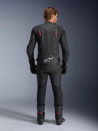 Chaqueta de cuero Alpinestars Dusk Airflow, negro y rojo flúor, vista trasera con perforaciones extensas y un gran logotipo blanco en la parte baja de la espalda, combinada con equipamiento de carreras de cuero a juego que incluye pantalones, botas y guantes
