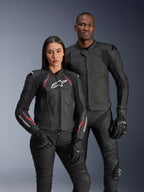 Chaquetas de cuero Alpinestars Dusk Airflow y Stella Dusk, pilotos hombre y mujer con chaquetas de cuero negro para motociclismo, la chaqueta de hombre cuenta con cuero perforado para ventilación, la chaqueta de mujer tiene detalles en rojo y logotipos blancos, coordinado con pantalones y guantes de conducción negros, equipamiento de conducción deportiva de alto rendimiento