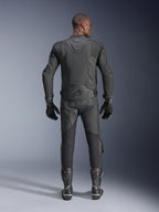 Modelo masculino visto desde atrás luciendo la chaqueta de cuero Alpinestars Dusk Airflow en color negro, combinada con pantalones de carreras de cuero negro, guantes y botas a juego, con perforaciones extensas para ventilación y el logotipo de Alpinestars en la parte inferior de la espalda.