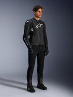 Chaqueta de cuero Alpinestars Dusk Airflow, negra y blanca, modelada con pantalones de moto, guantes y botas negros, con paneles de cuero perforado y logotipos blancos, estilo deportivo de competición en carretera.
