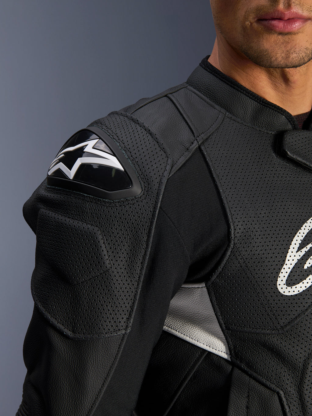 Chaqueta de cuero Alpinestars Dusk Airflow, negra y blanca, primer plano del hombro y el pecho, con cuero perforado para ventilación, protección de hombro DFS con el logotipo de Alpinestars en blanco y diseño deportivo.
