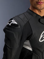 Chaqueta de cuero Alpinestars Dusk Airflow, negra y blanca, primer plano del hombro y el pecho, con cuero perforado para ventilación, protección de hombro DFS con el logotipo de Alpinestars en blanco y diseño deportivo.