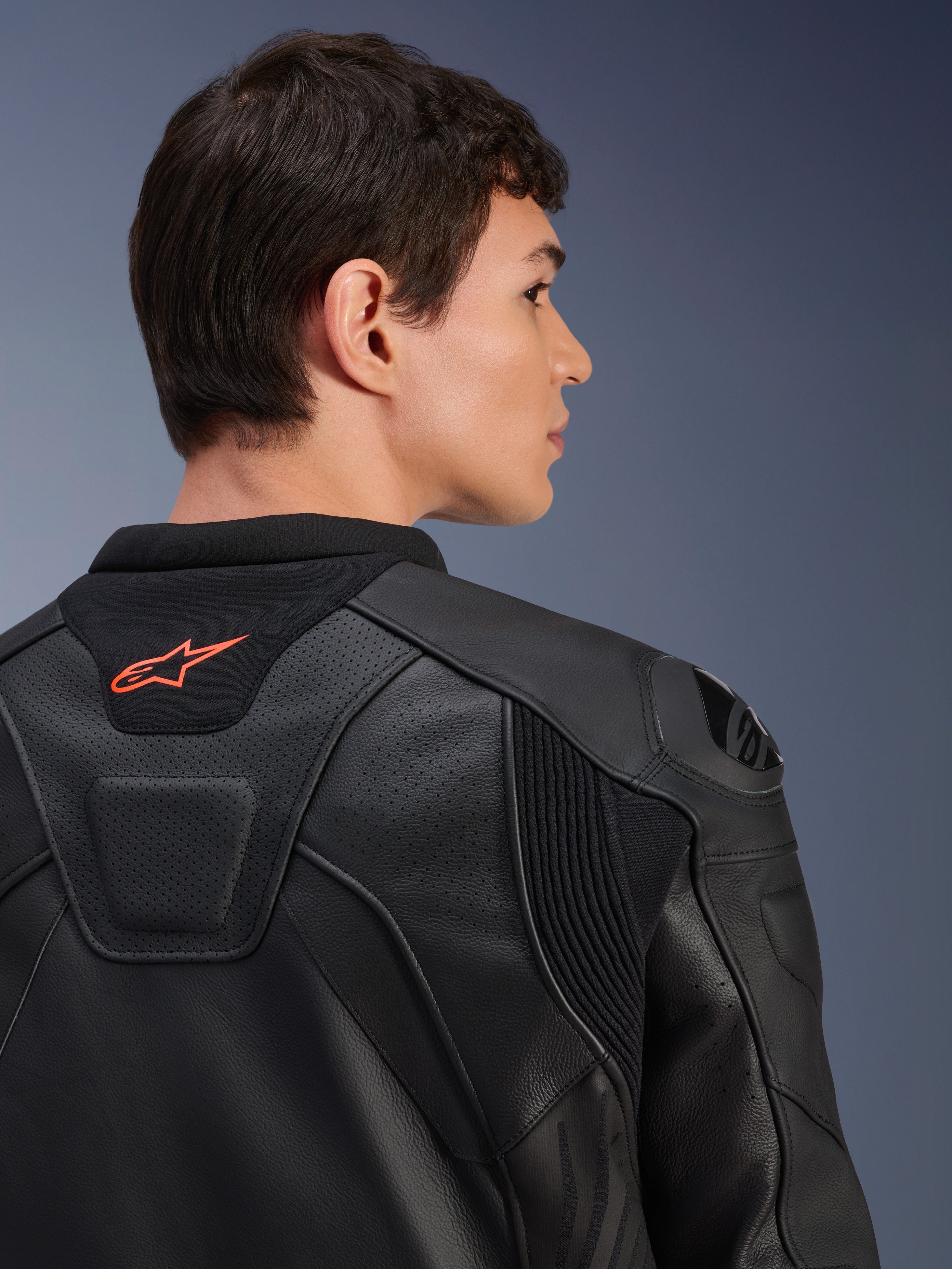 Chaqueta de cuero Alpinestars GP Plus R V4 Airflow, negra, primer plano de la vista trasera en un modelo, con cuero perforado de grado de competición, paneles elásticos técnicos y un pequeño logotipo naranja de Alpinestars en el cuello, equipo profesional para motociclismo