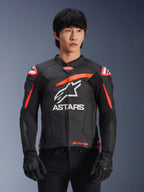 Chaqueta de cuero Alpinestars GP Plus R V4 Airflow en color negro con detalles en rojo fluo y blanco, vestida por un modelo, con construcción de cuero perforado, un gran logotipo ASTARS blanco en el pecho y protecciones de hombro integradas para carreras de motociclismo.