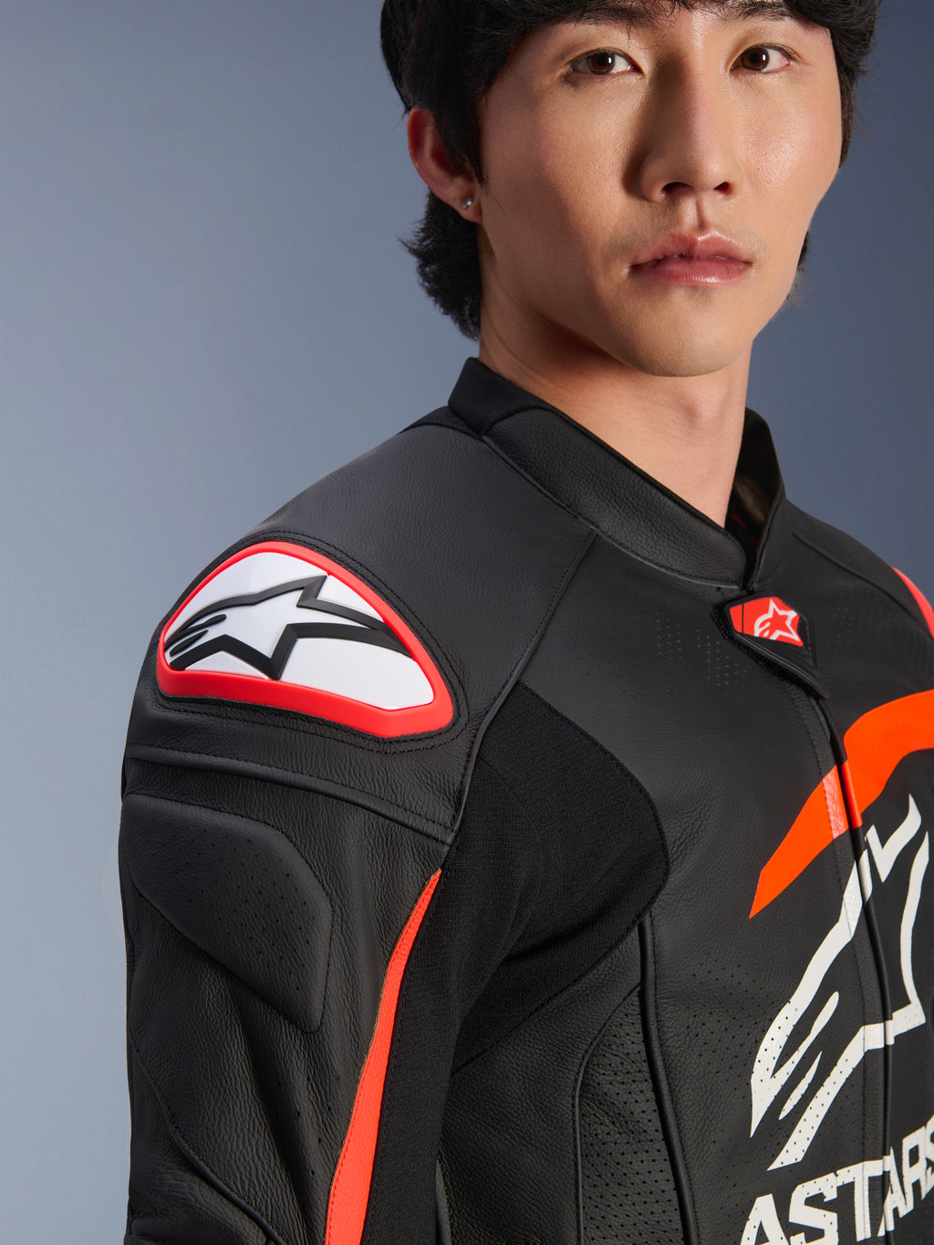 Alpinestars GP Plus R V4 Airflow Leather Jacket, negro, rojo flúor y blanco, primer plano de un modelo con la chaqueta, con el destacado logo Astar en el deslizador del hombro y cuero perforado en el pecho para un flujo de aire máximo, ropa profesional de motociclismo
