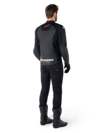 Alpinestars Faster V3 Leather Jacket, chaqueta de moto deportiva, negro y rojo flúor, vista trasera usada con pantalones negros y botas negras, con el texto 'alpinestars RACING AHEAD' en la parte baja de la espalda y un pequeño logotipo de estrella roja, confección de cuero con ajuste deportivo estilizado