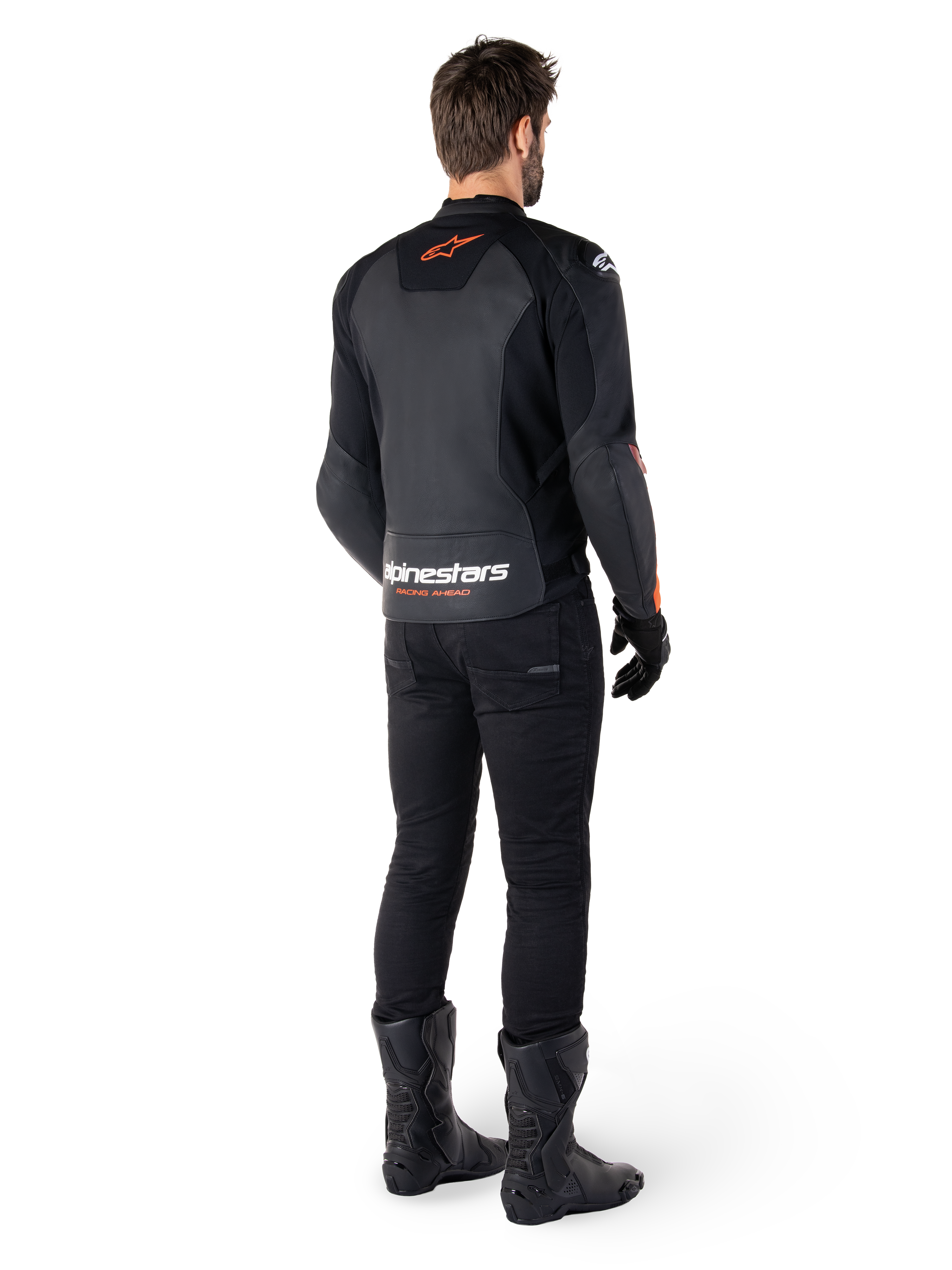 Alpinestars Faster V3 Leather Jacket, chaqueta de moto deportiva, negro y rojo flúor, vista trasera usada con pantalones negros y botas negras, con el texto 'alpinestars RACING AHEAD' en la parte baja de la espalda y un pequeño logotipo de estrella roja, confección de cuero con ajuste deportivo estilizado