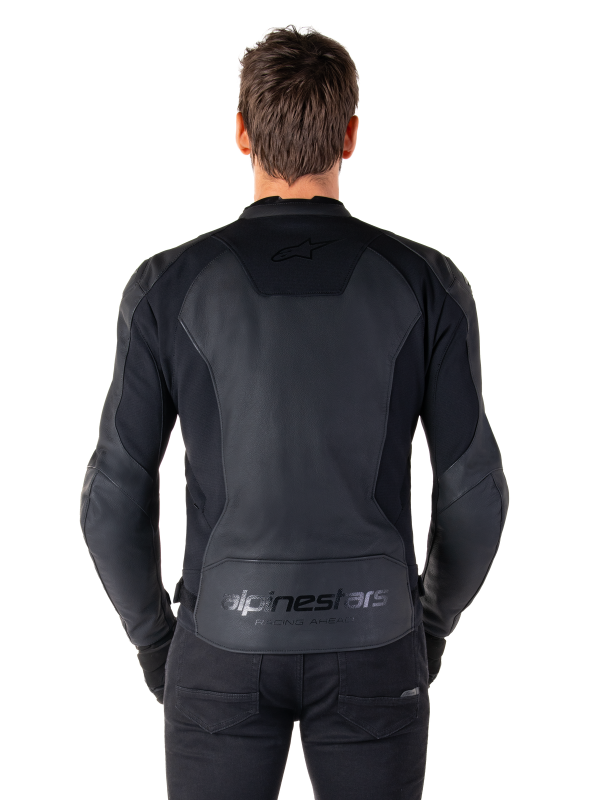 Vista posterior de un hombre con la chaqueta de cuero Alpinestars Faster V3 en color negro, con paneles de cuero premium e inserciones elásticas flexibles, logotipos sutiles de 'alpinestars' y 'RACING AHEAD' en la parte baja de la espalda, ajuste deportivo para conducción de motocicleta