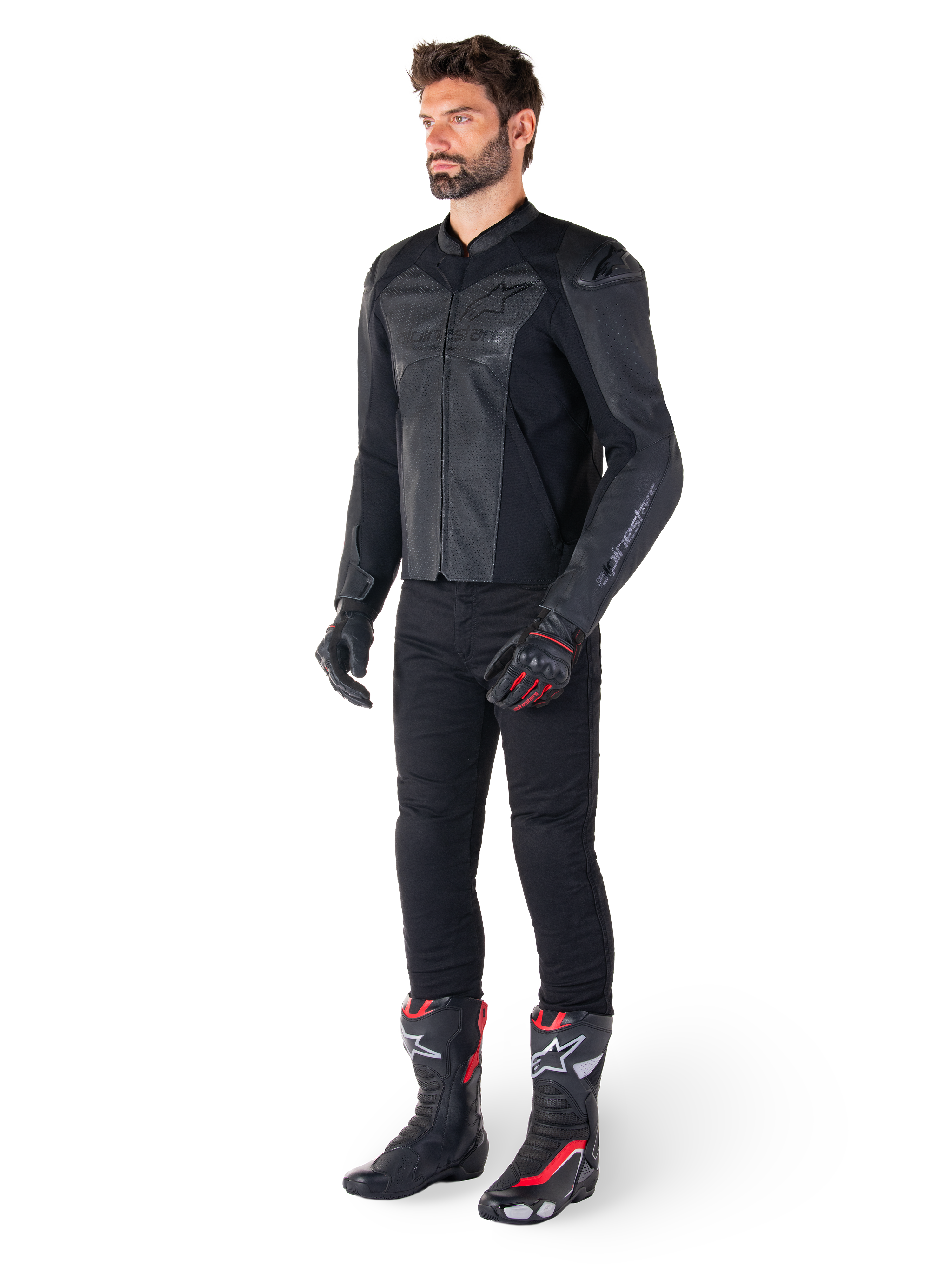 Hombre vistiendo la chaqueta de cuero Alpinestars Faster V3 Airflow en color negro, combinada con pantalones negros, guantes de moto negros y rojos, y botas de competición negras con detalles rojos y blancos, equipamiento de conducción deportiva de cuerpo completo