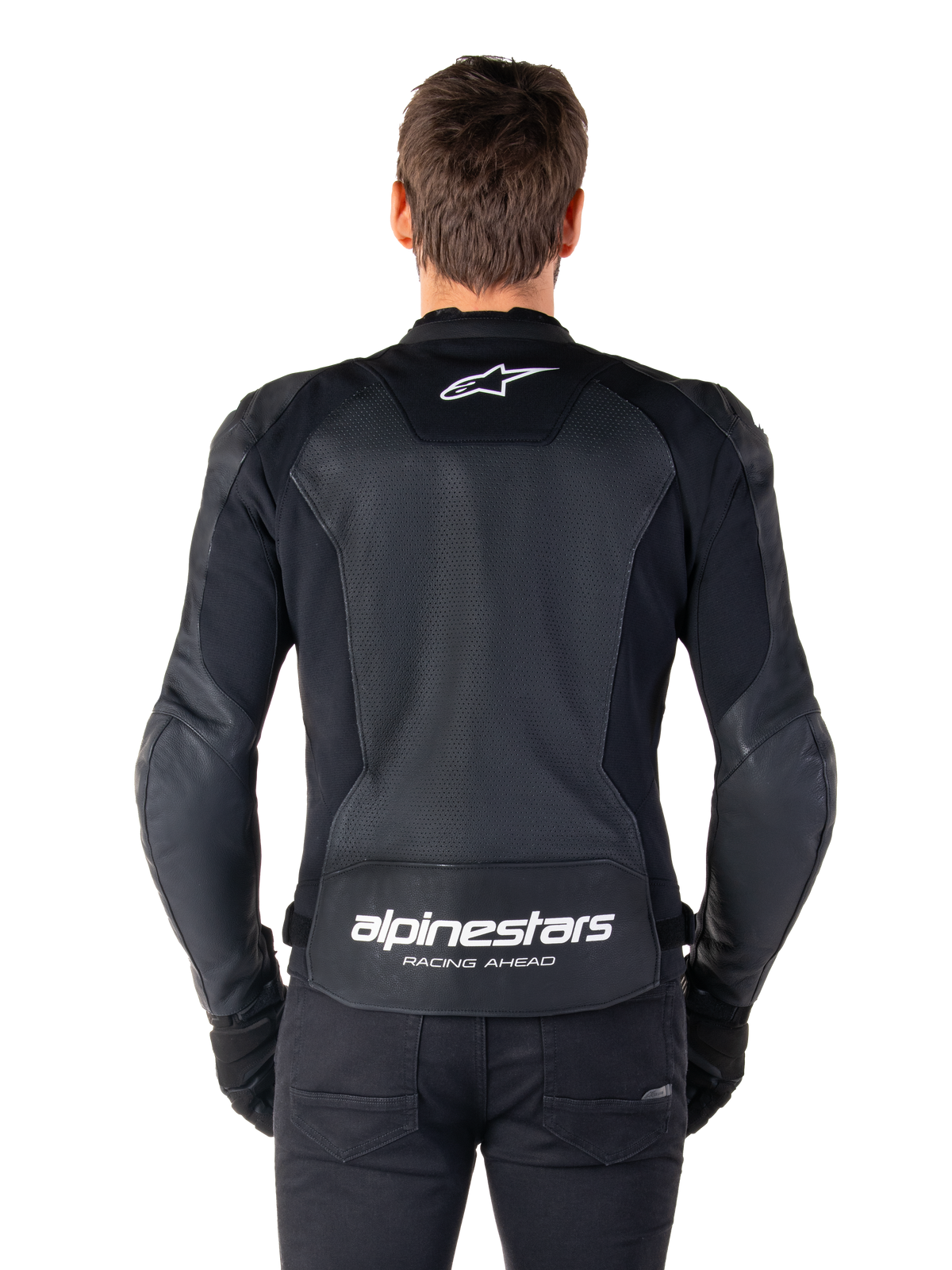Chaqueta de cuero Alpinestars Faster V3 Airflow, negro y blanco, vista trasera de un piloto mostrando el panel de cuero perforado en la espalda para ventilación, logotipo blanco de Alpinestars en la parte superior de la espalda y marca 'RACING AHEAD' en la parte inferior, equipamiento de motociclismo con ajuste deportivo.