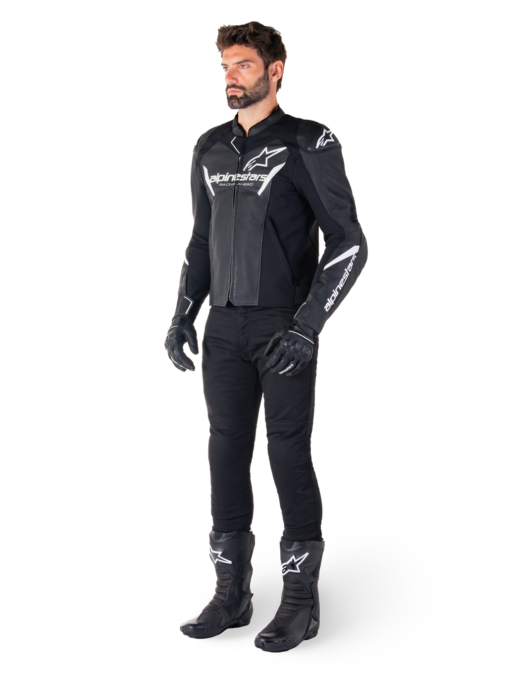Modelo con la chaqueta de cuero Alpinestars Faster V3 Airflow, negra y blanca, con cuero perforado y logotipos Alpinestars blancos, combinada con pantalones, guantes y botas de conducción negros, equipamiento de motociclismo de estilo deportivo