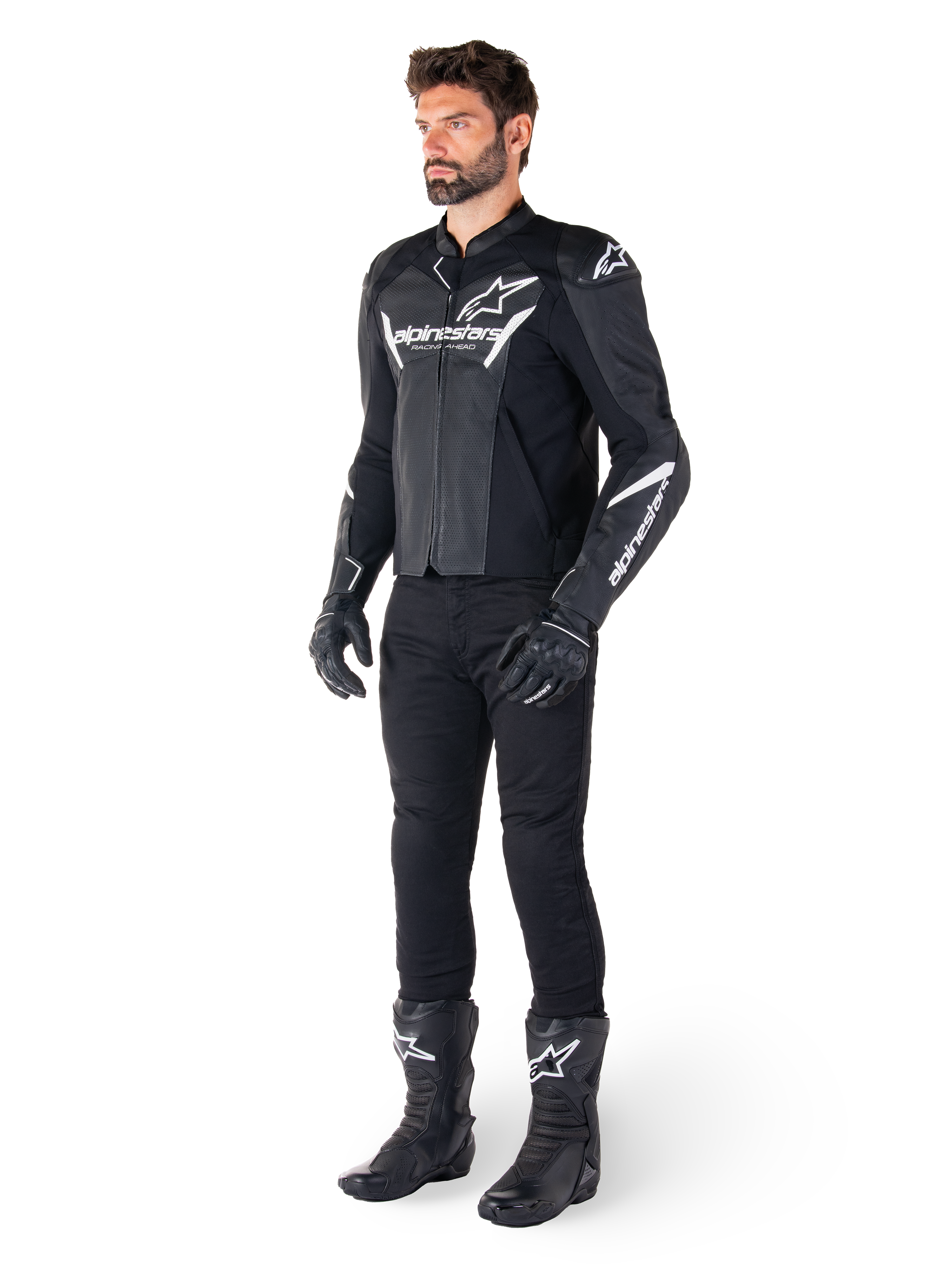 Modelo con la chaqueta de cuero Alpinestars Faster V3 Airflow, negra y blanca, con cuero perforado y logotipos Alpinestars blancos, combinada con pantalones, guantes y botas de conducción negros, equipamiento de motociclismo de estilo deportivo