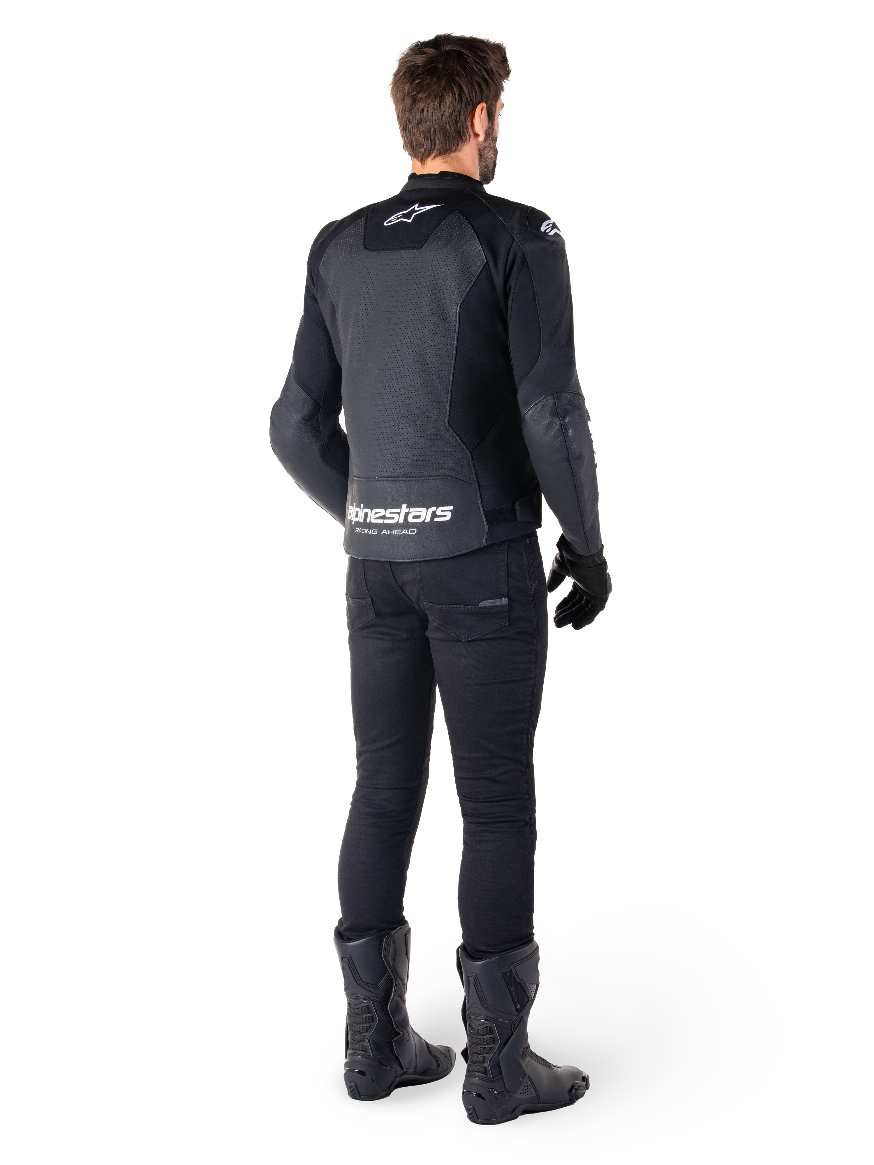 Chaqueta de cuero Alpinestars Faster V3 Airflow, negro y blanco, vista posterior que muestra los paneles de cuero perforados y el logotipo de Alpinestars en la parte baja de la espalda, vestida por un piloto con pantalones, guantes y botas de motorista negros.