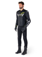 Piloto masculino con la chaqueta de cuero Alpinestars Faster V3 Airflow en negro, blanco y amarillo flúor, combinada con pantalones y botas de moto negros, con paneles de cuero perforado, detalles de logotipos en blanco y acentos en amarillo neón, equipamiento profesional de conducción deportiva