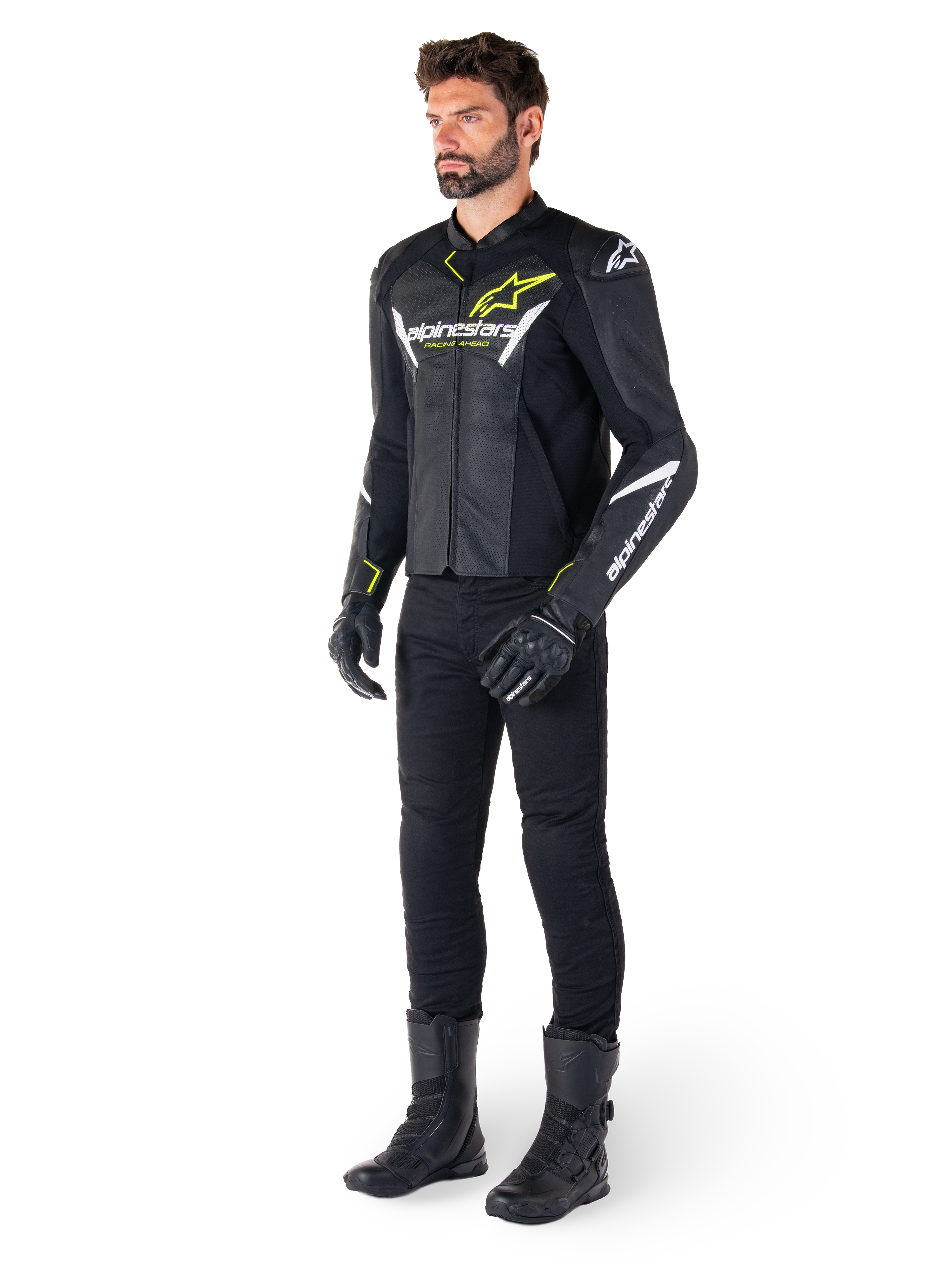 Piloto masculino con la chaqueta de cuero Alpinestars Faster V3 Airflow en negro, blanco y amarillo flúor, combinada con pantalones y botas de moto negros, con paneles de cuero perforado, detalles de logotipos en blanco y acentos en amarillo neón, equipamiento profesional de conducción deportiva
