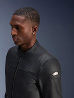Alpinestars Blacktrack Leather Jacket, premium black bovine leather, close-up profile view of a man wearing the jacket, featuring metallic gunmetal front zip, high buttoned collar, and metallic shoulder badge with logo, sleek tailored motorcycle jacket