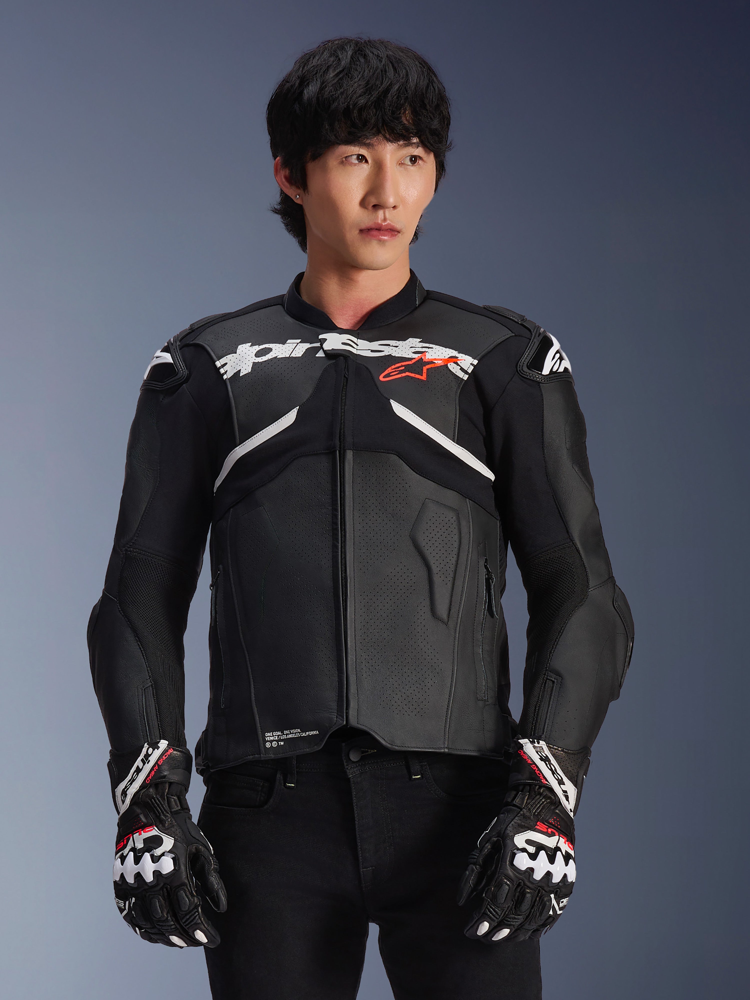 Chaqueta de cuero Alpinestars Atem V5, chaqueta de carreras para moto, negra con detalles en blanco y rojo, construcción de cuero premium con protecciones, usada con guantes de carreras a juego