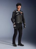Chaqueta de cuero Alpinestars Atem V5, chaqueta de carreras para moto, negra y blanca, usada con pantalones negros y guantes a juego, con la marca Alpinestars en blanco sobre el pecho y protecciones en los hombros