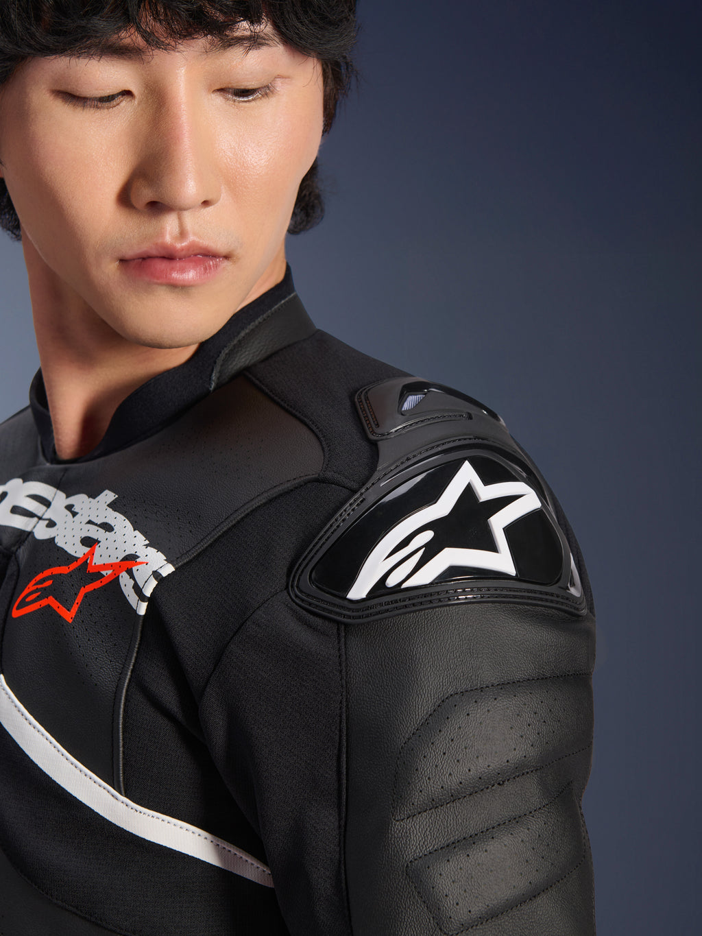 Primer plano de la chaqueta de cuero Alpinestars Atem V5 en negro y blanco, con el protector de hombro DFS RR con el logotipo de la estrella blanca, construcción de cuero perforado y gráficos en el pecho inspirados en la competición.