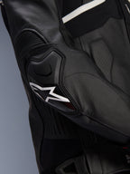 Chaqueta de cuero Alpinestars Atem V5, negro y blanco, primer plano del protector de codo DFS RR con logo de estrella blanca, con cuero en acordeón y texturas perforadas para conducción deportiva