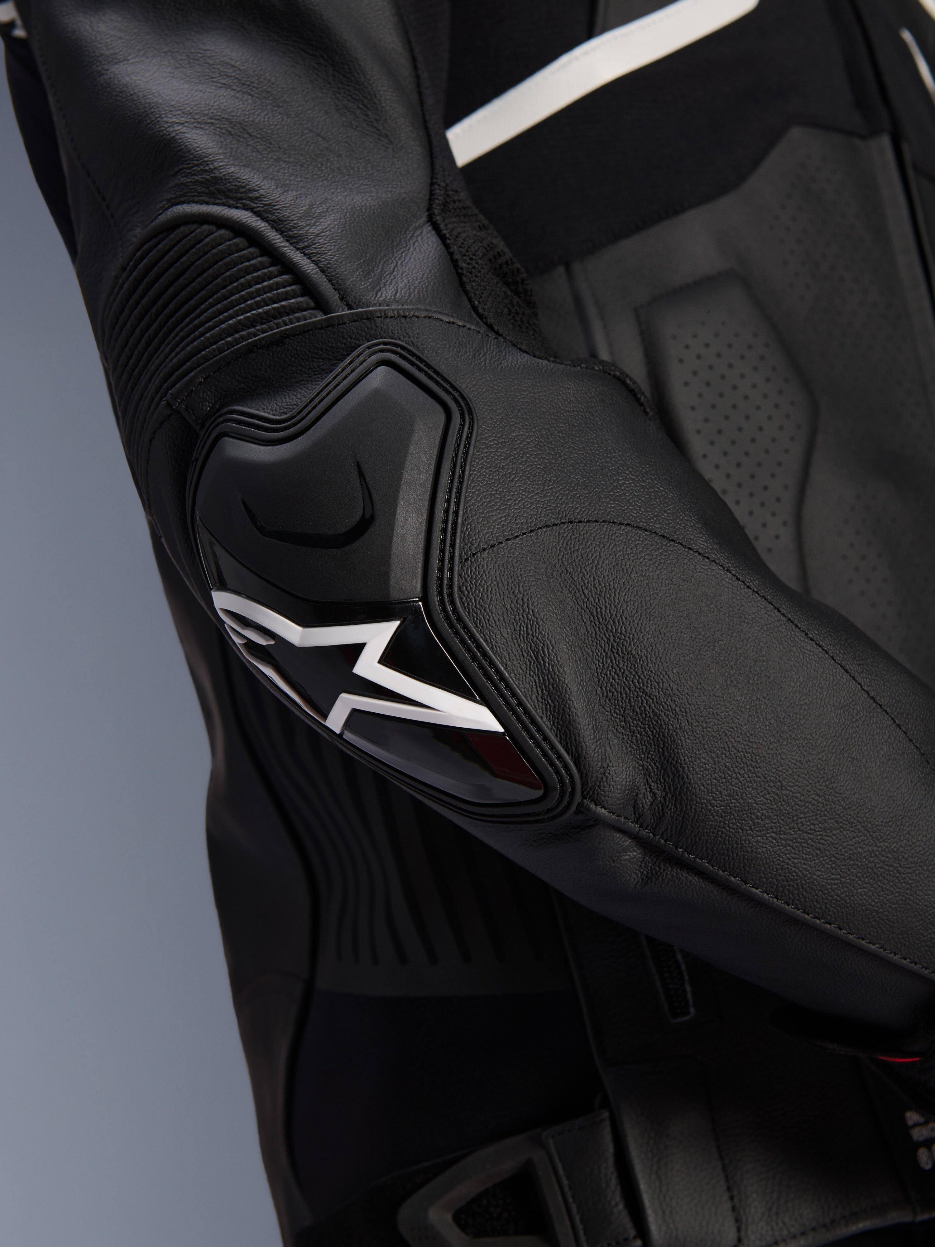 Chaqueta de cuero Alpinestars Atem V5, negro y blanco, primer plano del protector de codo DFS RR con logo de estrella blanca, con cuero en acordeón y texturas perforadas para conducción deportiva