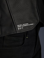 Primer plano de la chaqueta de cuero Alpinestars Atem V5 en color negro, con el panel inferior de la espalda que incluye la inscripción 'ONE GOAL. ONE VISION. VENICE / LOS ANGELES CALIFORNIA' y textura de cuero perforado.
