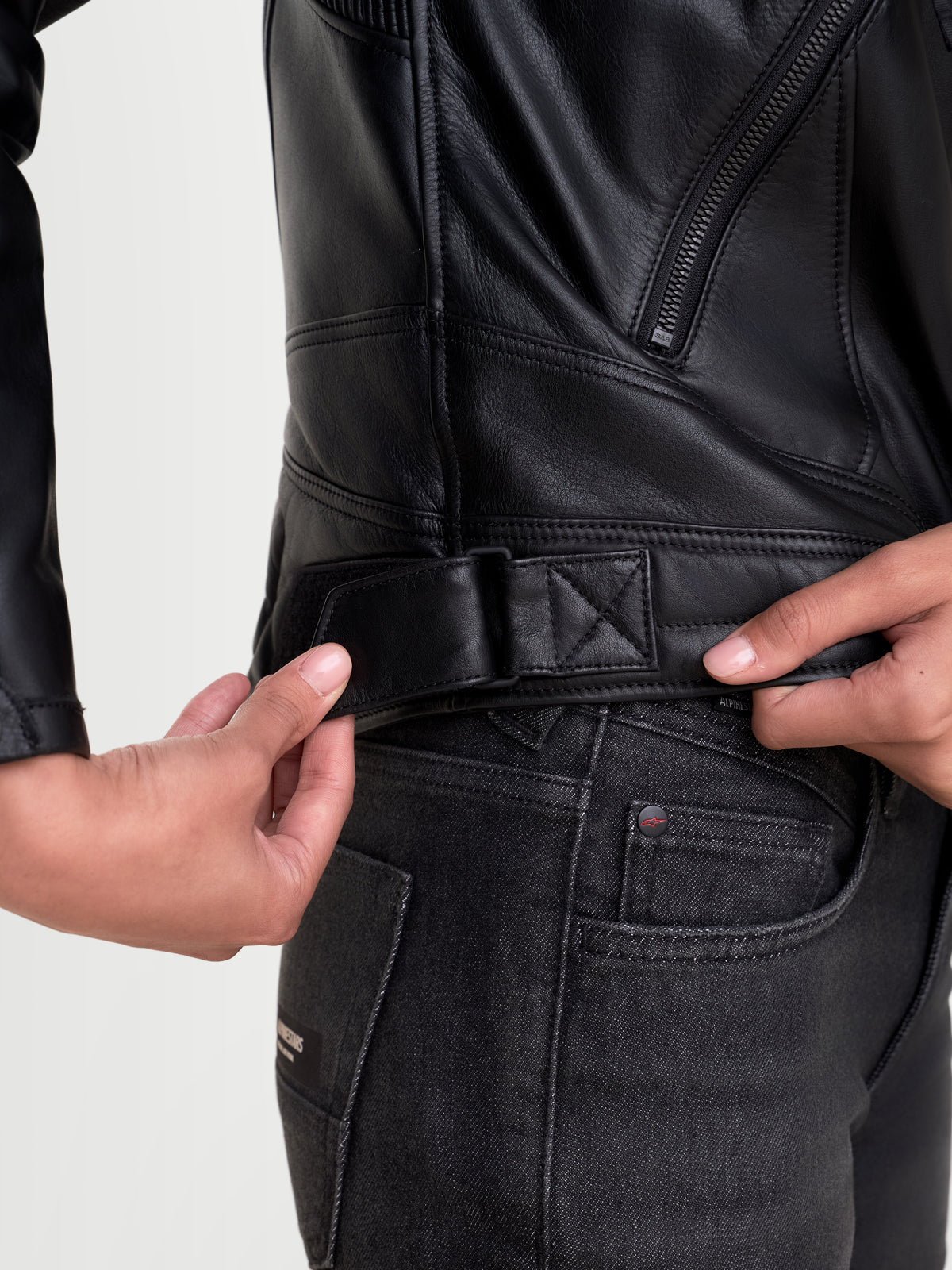 Alpinestars Revea Women Leather Jacket, urban motorcycle leather jacket in black, close-up view of the waist adjustment tab and full-grain bovine leather construction worn by a model.
