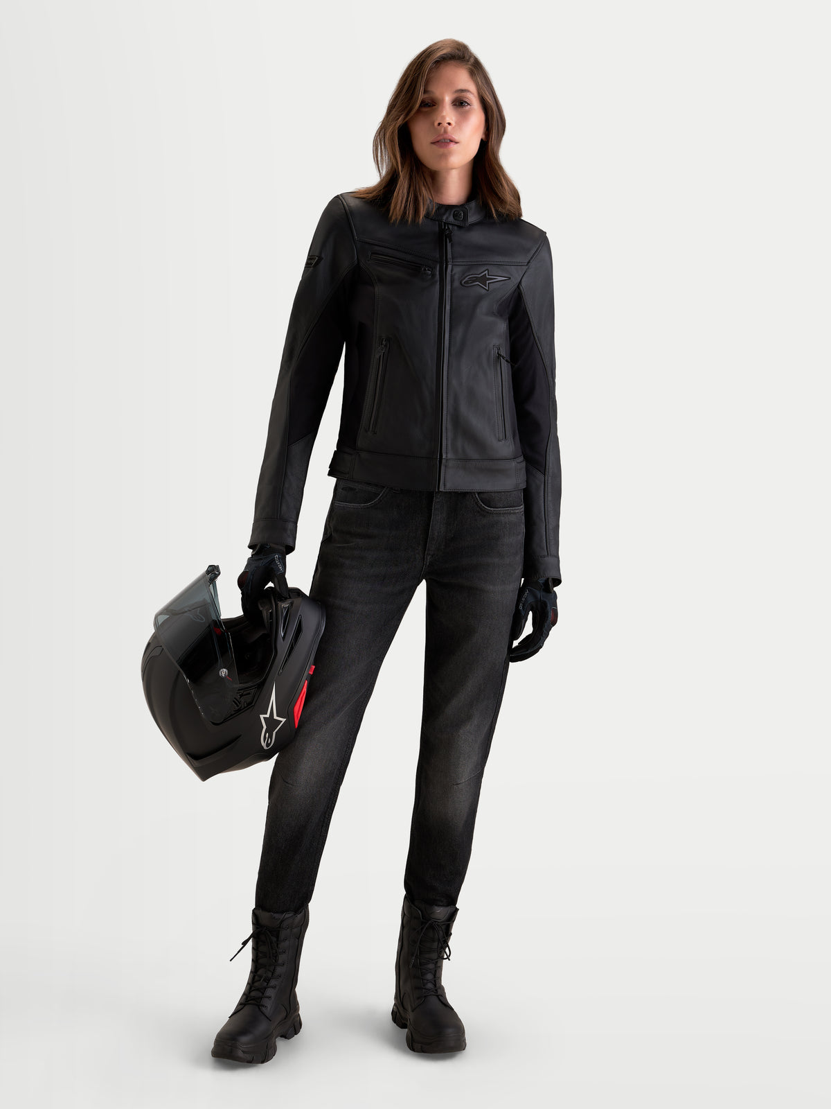 Alpinestars Stella Maver-X Leather Jacket, women's urban motorcycle leather jacket in black, front view worn by a model holding a helmet and wearing riding boots