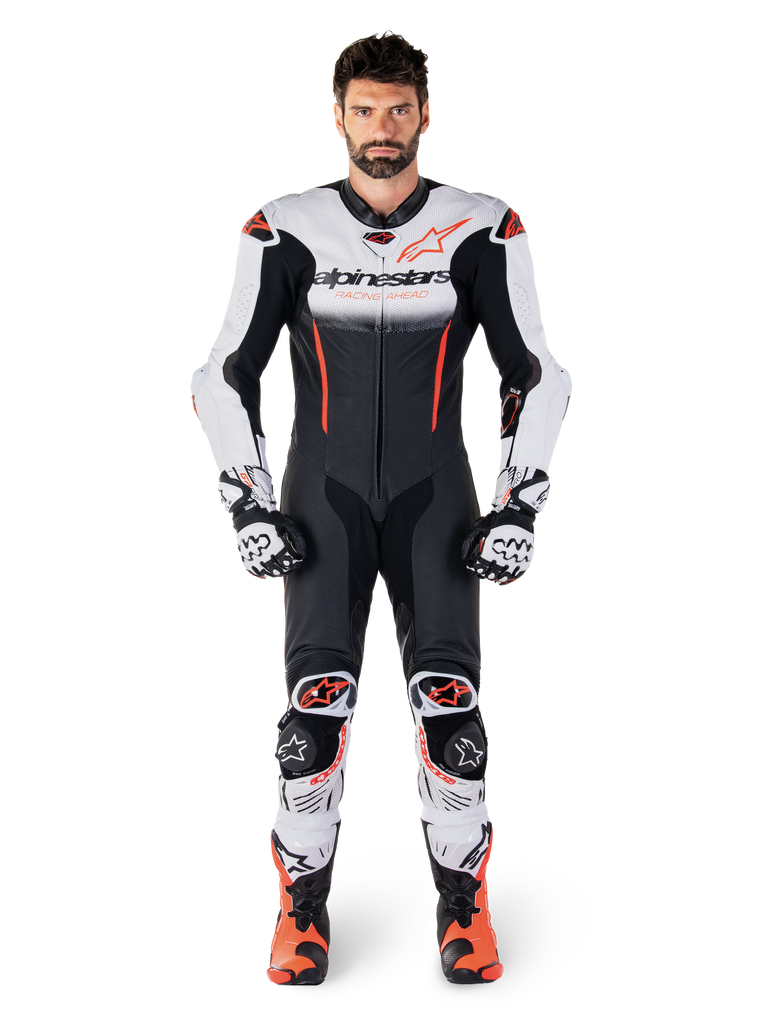 Piloto luciendo el mono de cuero de una pieza Alpinestars GP-R7 en blanco, negro y rojo flúor, coordinado con guantes y botas de competición a juego, equipamiento profesional de motociclismo para pista con un ajuste de carreras aerodinámico y logotipos llamativos
