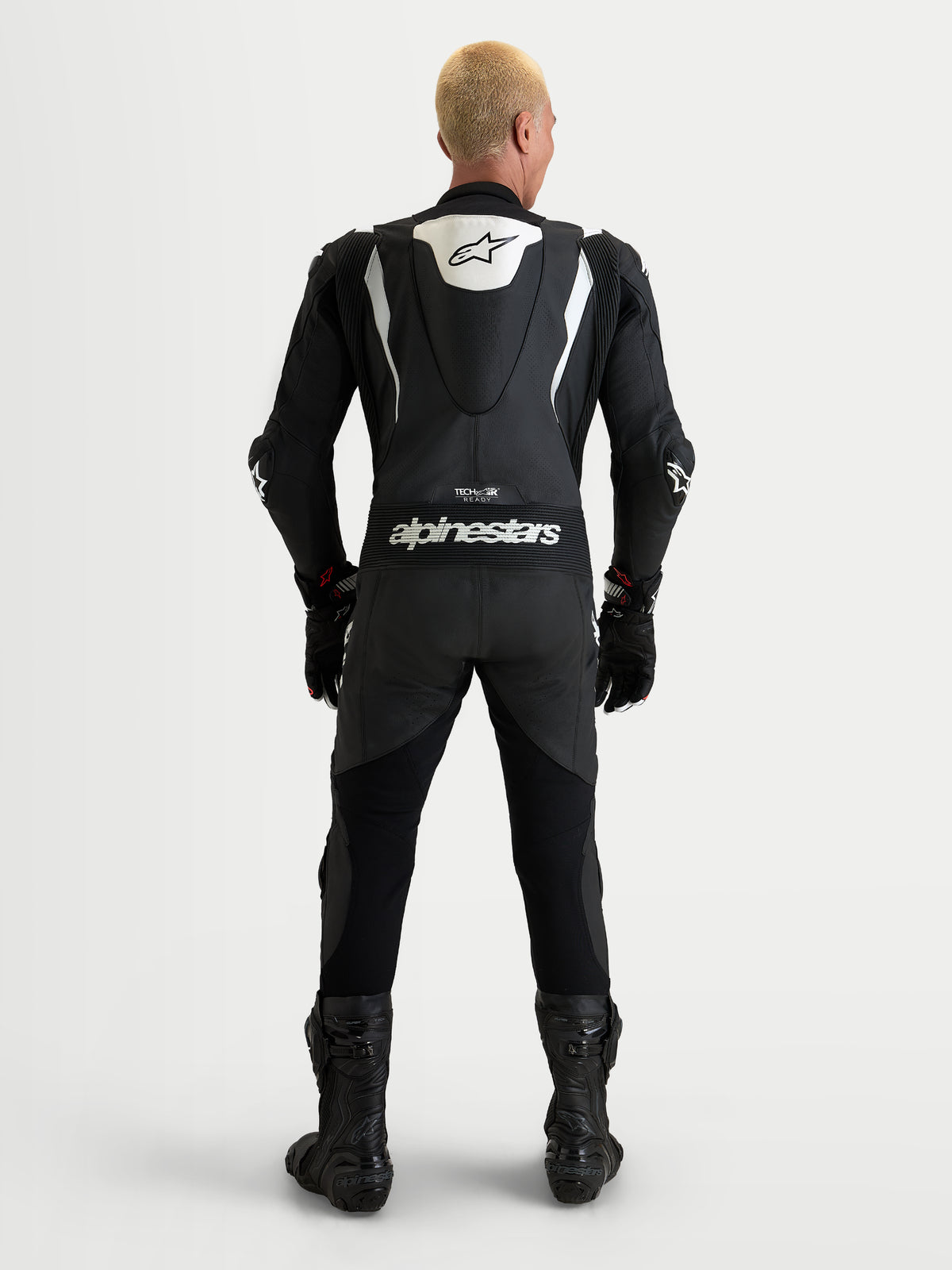 Alpinestars Missile V3 Leather Suit 1 Piece, mono de cuero para moto de una pieza, negro y blanco, vista trasera con joroba aerodinámica y branding de Alpinestars en el modelo