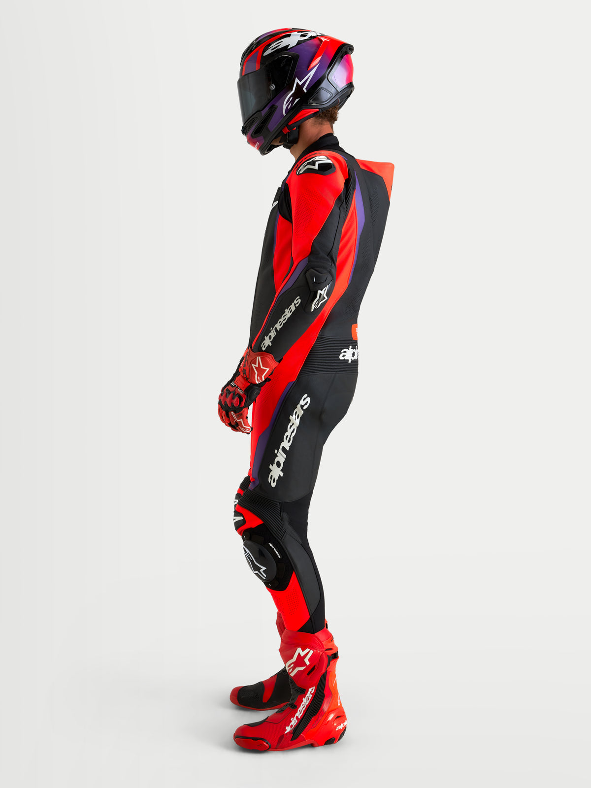 Mono de cuero Alpinestars Missile V3 de una pieza para moto, negro, rojo y morado, con joroba aerodinámica y protecciones, vista lateral en modelo
