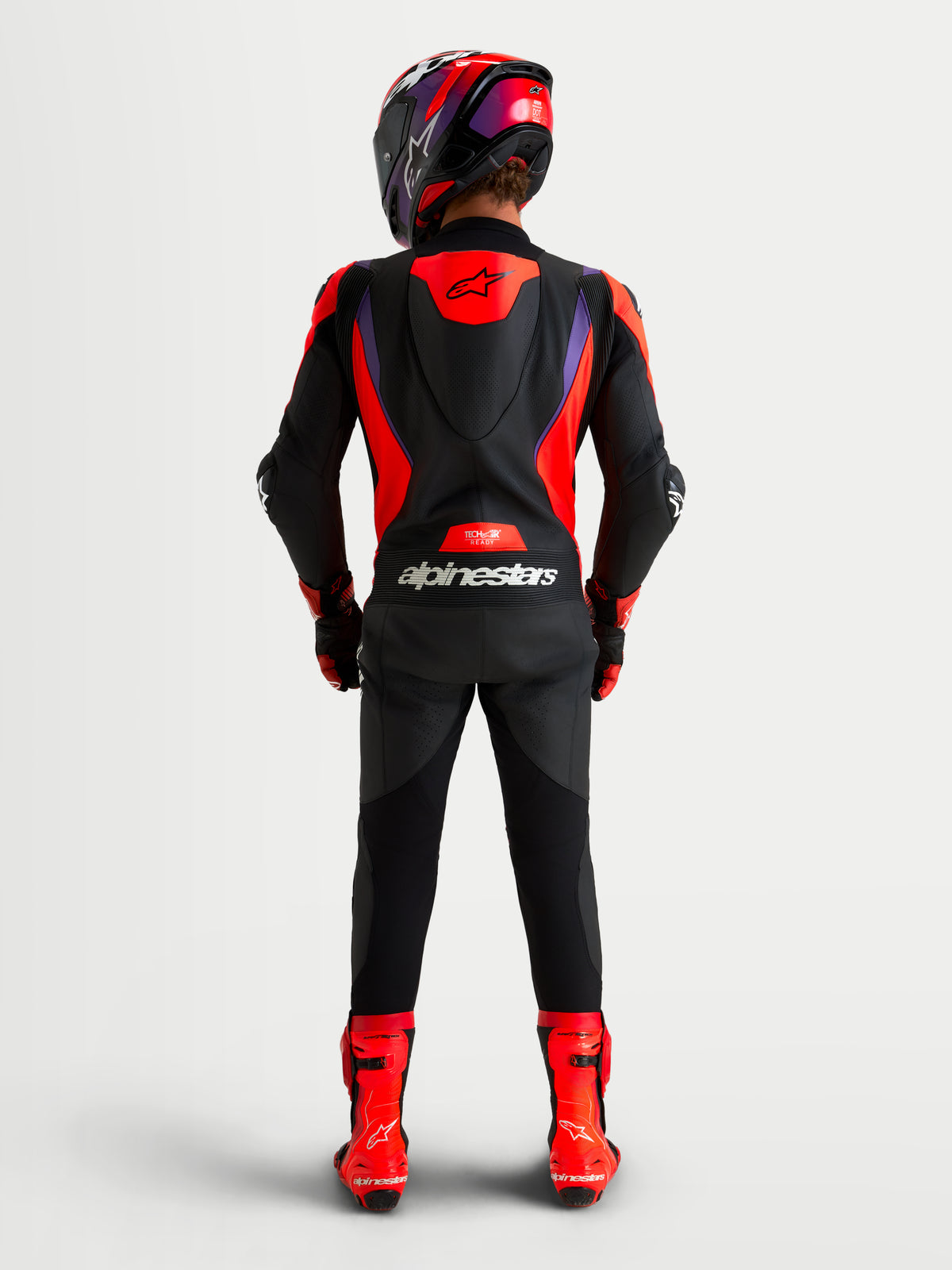 Alpinestars Missile V3 mono de cuero de una pieza, mono de carreras negro, rojo y morado con joroba aerodinámica y protección con certificación CE, vista trasera con casco y botas a juego