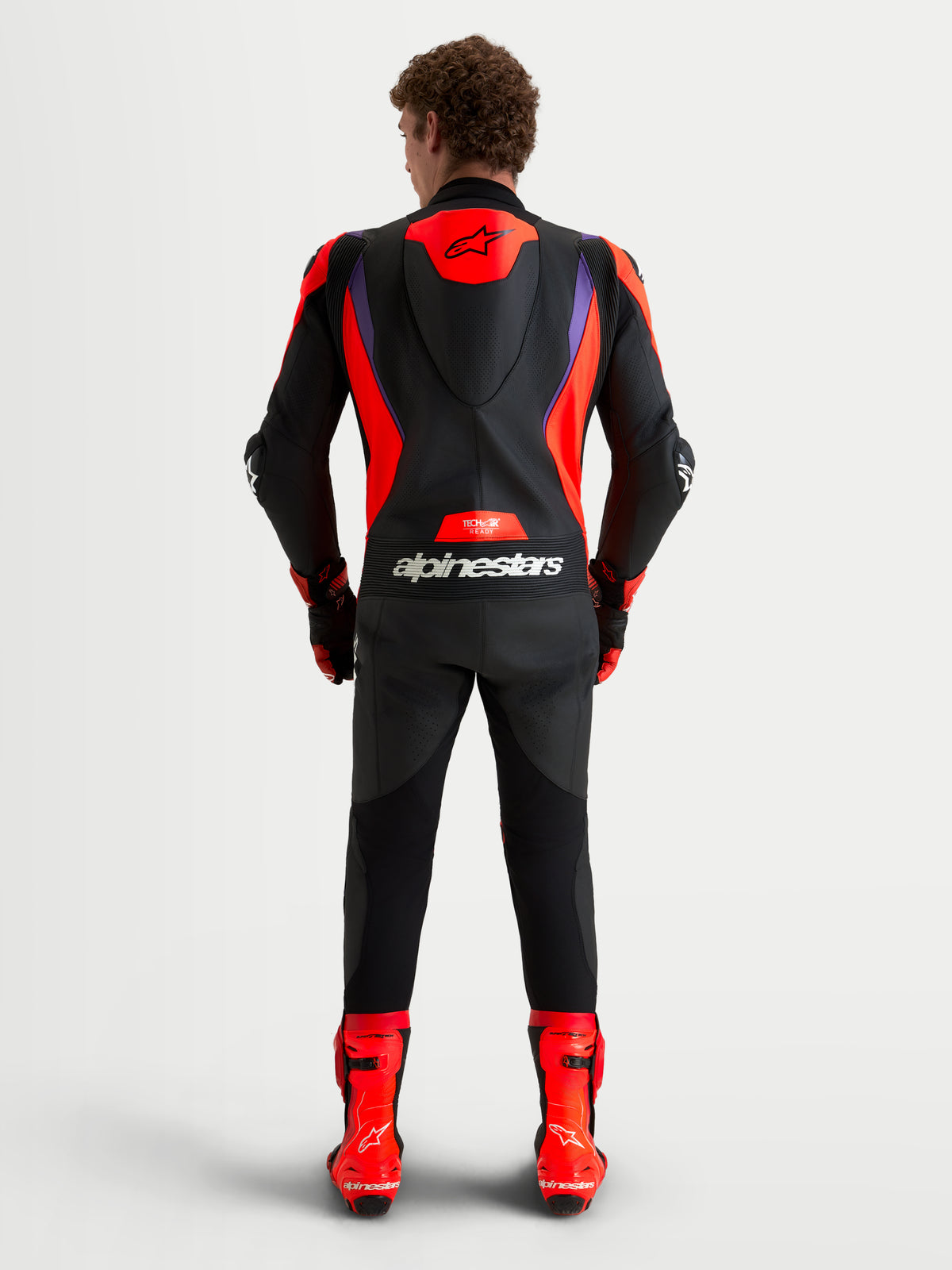 Alpinestars Missile V3 mono de cuero de 1 pieza, mono de moto de carreras, negro, rojo y morado, con joroba aerodinámica, protección DFS y diseño compatible con Tech-Air, vista trasera en modelo