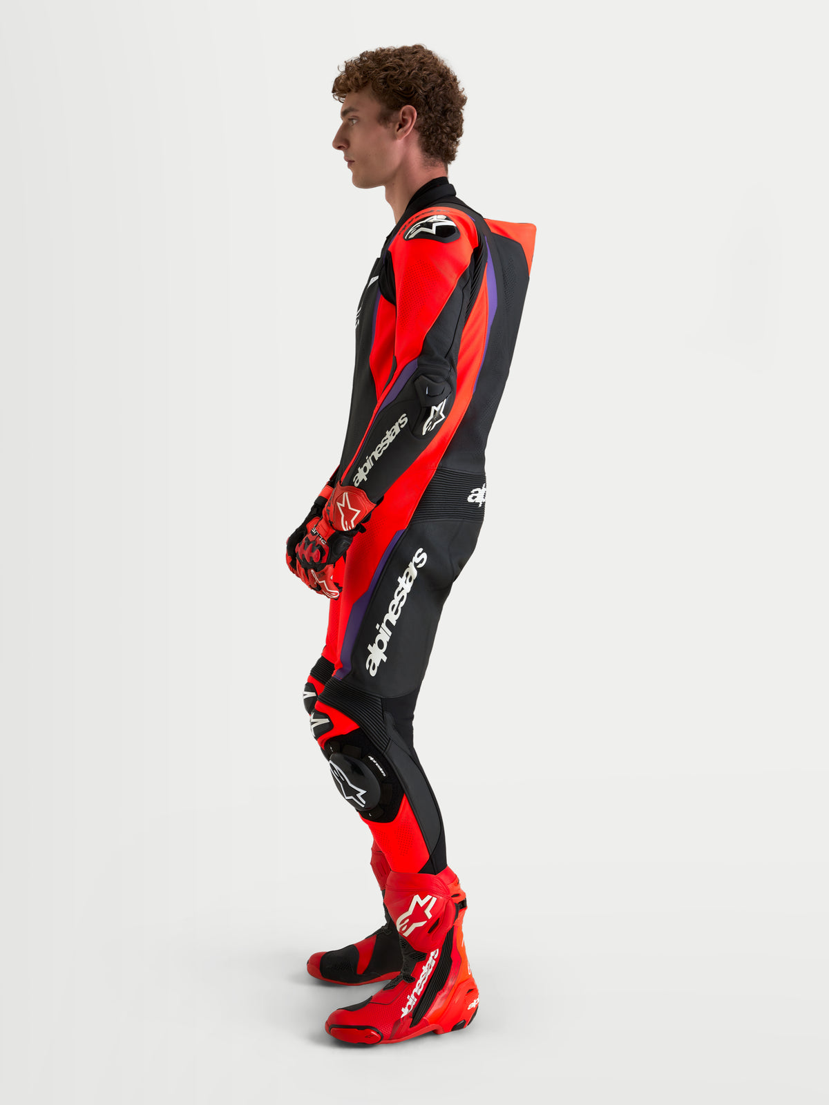 Alpinestars Missile V3 Leather Suit - 1 Piece, mono de moto de cuero para hombre con certificación AAA, negro, rojo y morado, con protección integrada DFS y joroba aerodinámica, visto de perfil en modelo
