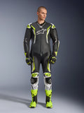 Alpinestars GP Tech V5 One Piece Leather Suit, mono de carreras profesional para motociclismo en negro y amarillo neón flúor con detalles blancos, vestido por un modelo con guantes y botas de carreras a juego, con un diseño aerodinámico y deslizadores de protección.