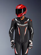 Piloto de motociclismo con traje de cuero de una pieza Alpinestars GP Force V2 en Negro Blanco Rojo Fluo, casco y guantes de carreras rojos a juego, con paneles de cuero perforado y logotipos llamativos, equipo de carreras de alto rendimiento